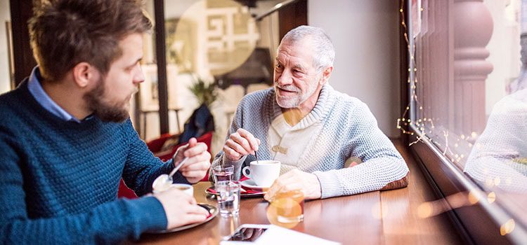 Man and elderly man bonding in a café