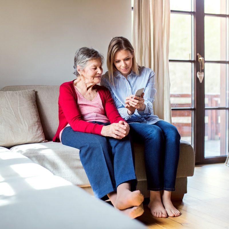 Woman showing elderly woman something on her phone