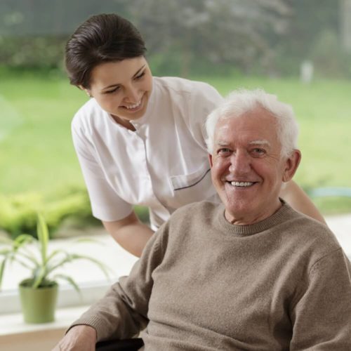 Caregiver smiling and standing behind elderly man