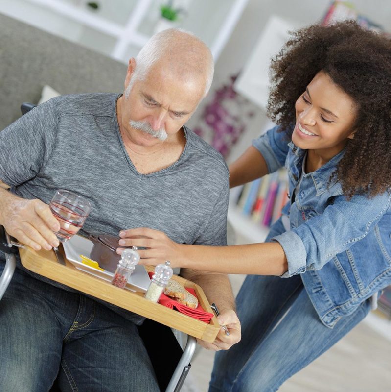 Woman helping elderly man with meal