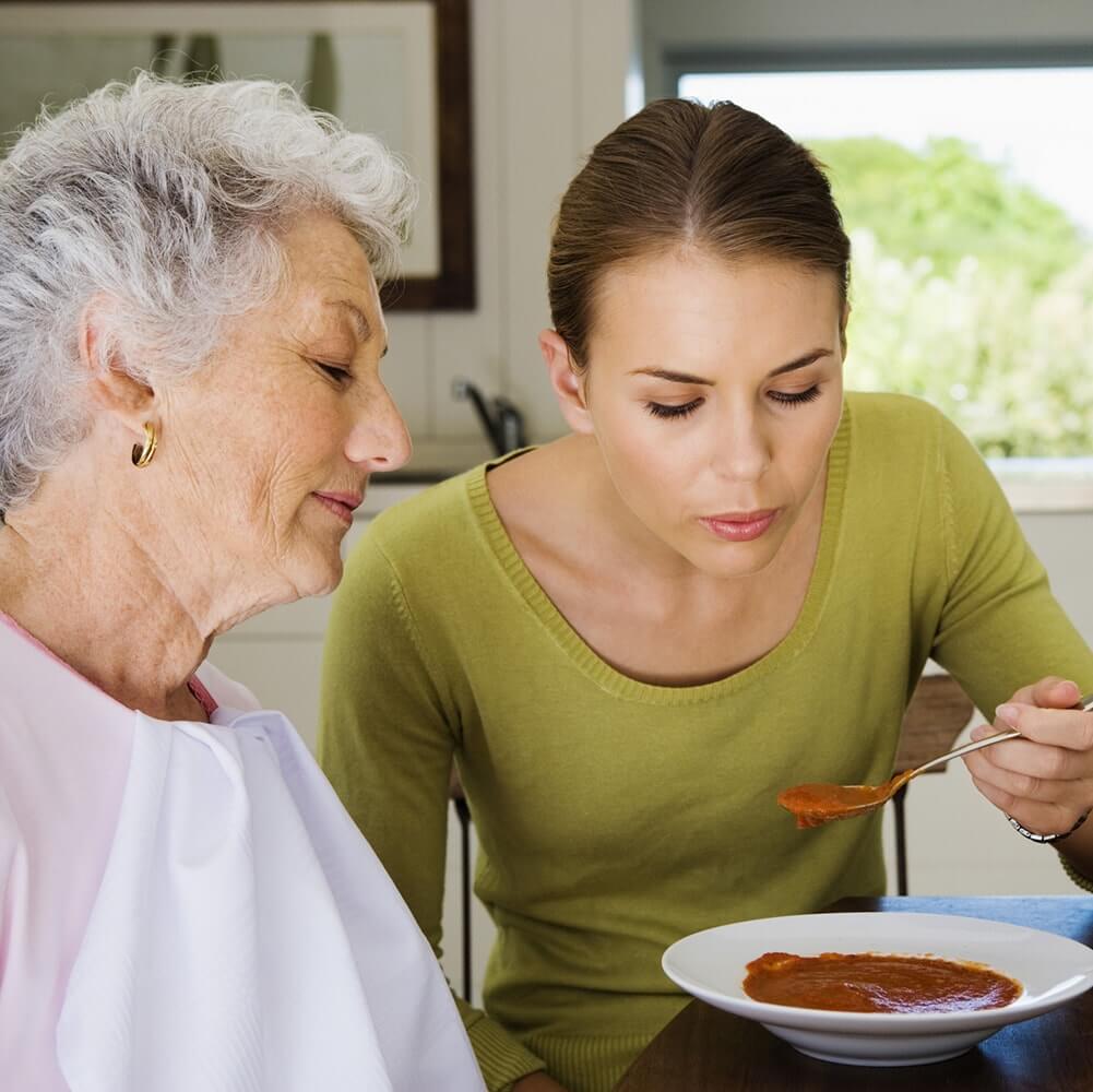 Woman feeding elderly woman