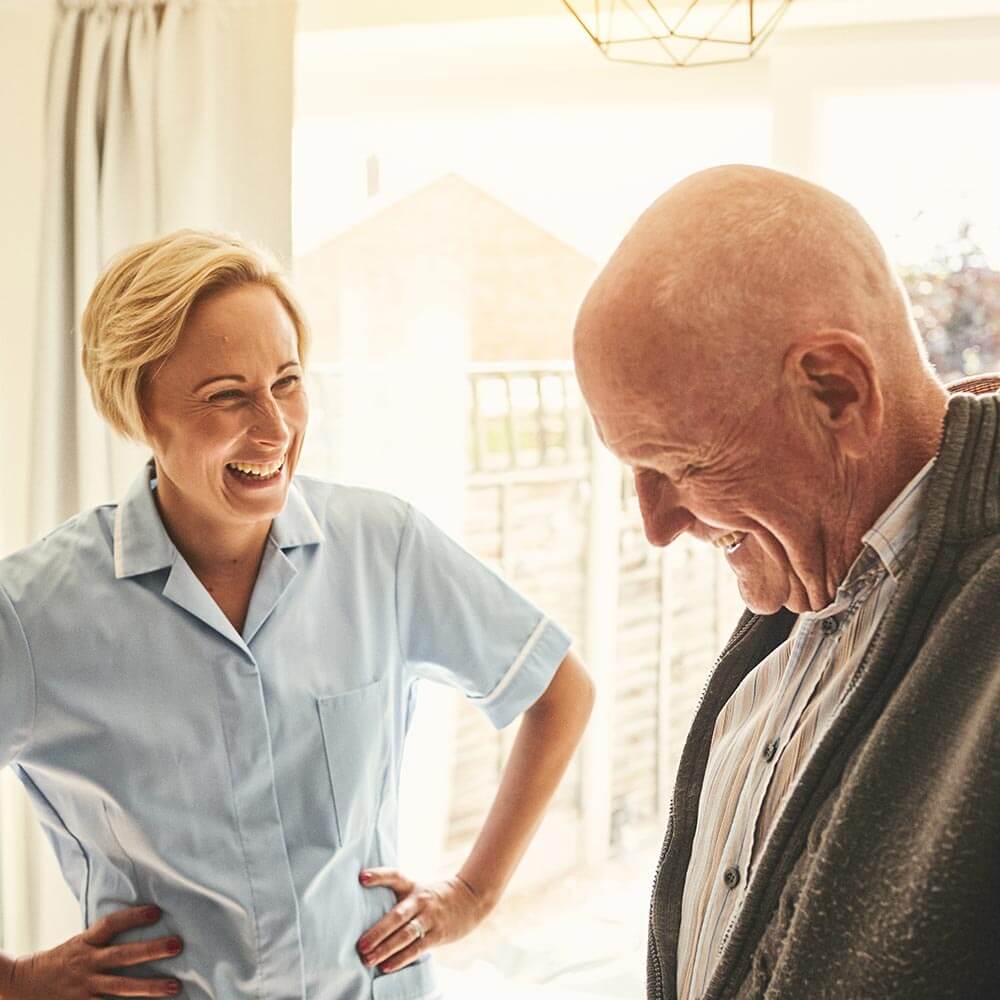 Caregiver laughing with elderly man