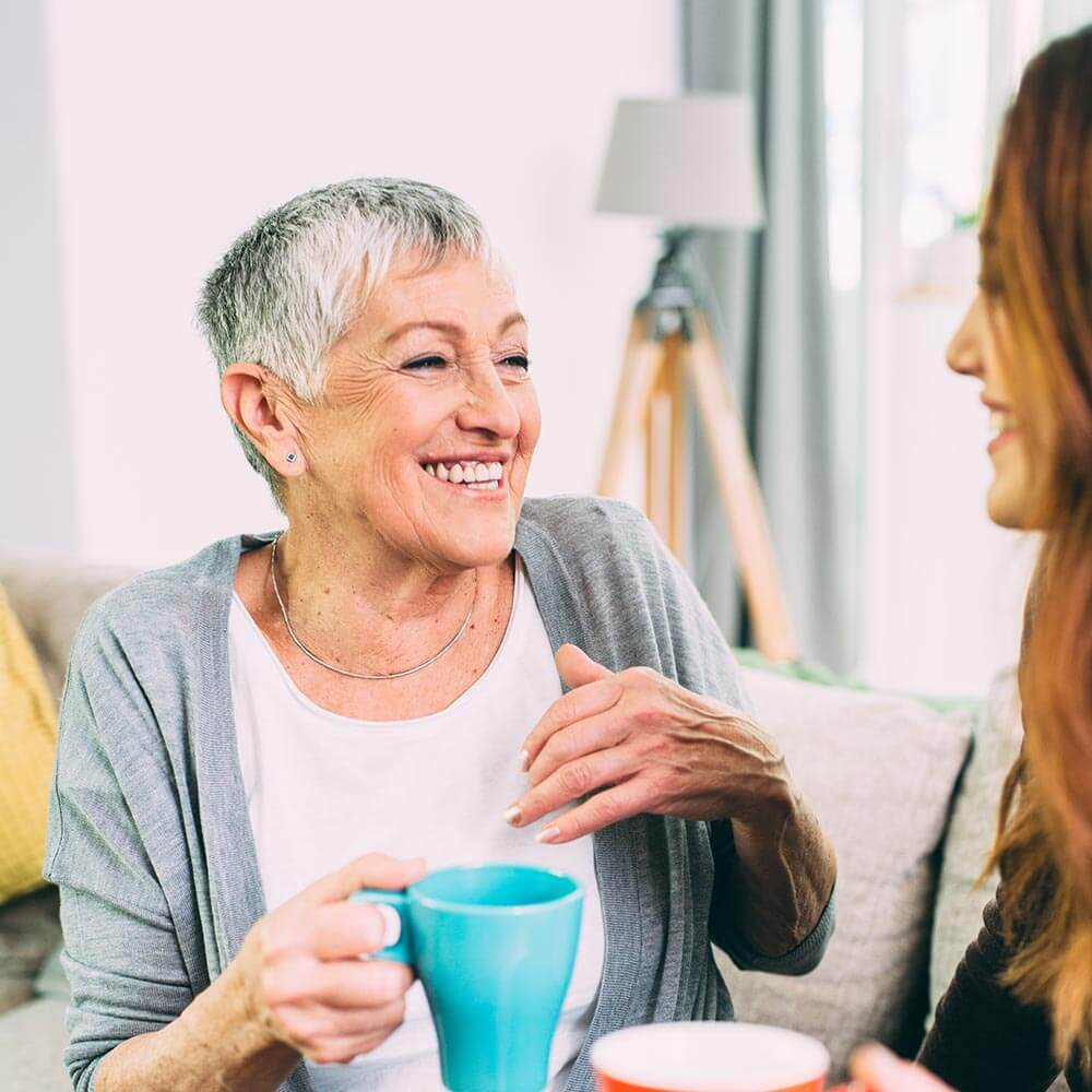 Elderly woman laughing with younger woman
