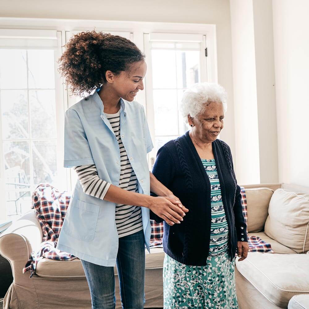 Caregiver helping elderly woman walk