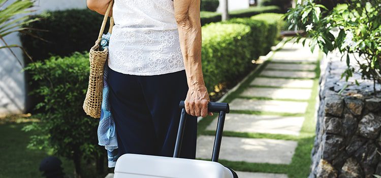 Elderly woman walking away with a suitcase
