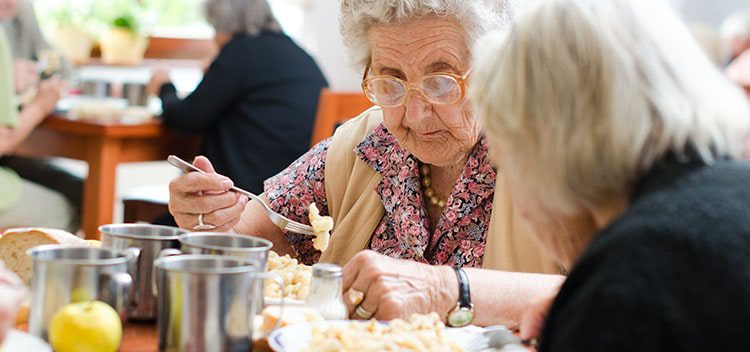 Elderly woman eating with friends