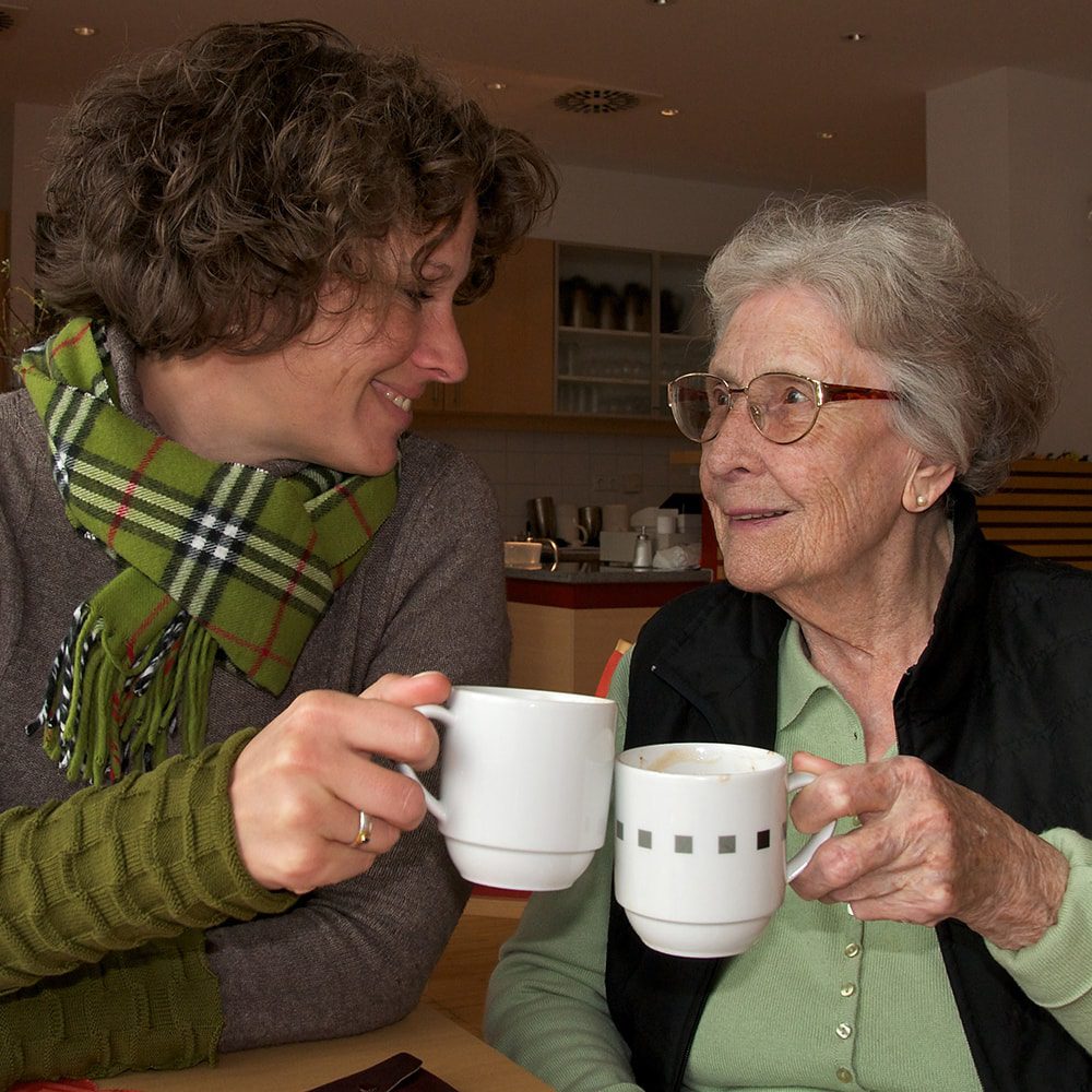 Woman and elderly woman toasting with two cups