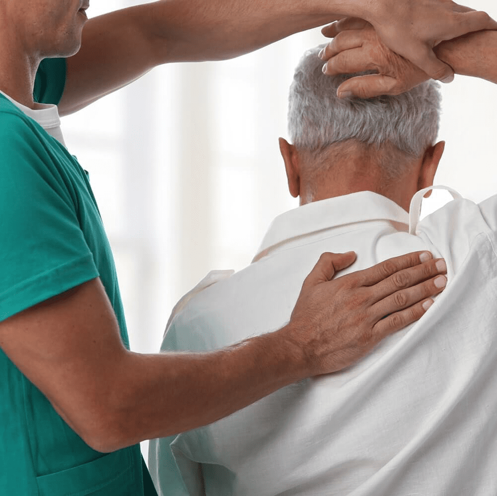 Carer helping elderly man with stretches