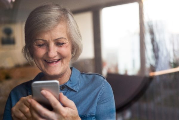 Elderly woman smiling and scrolling through smartphone