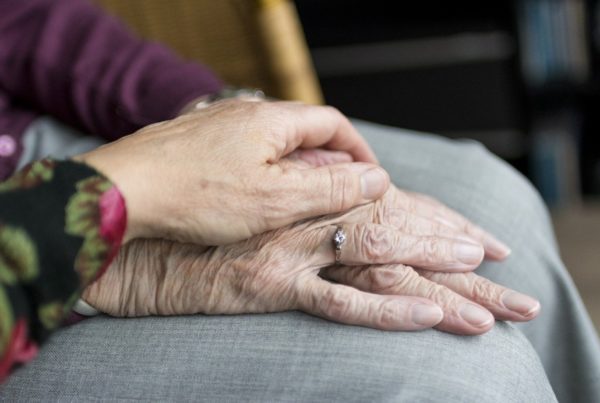 A hand placed on top of an elderly hand in a show of comfort and support