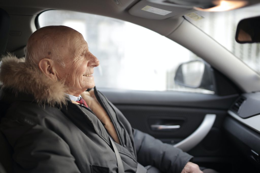 Elderly gentleman sat in car, smiling