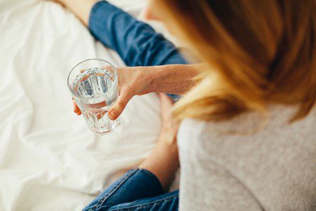 Lady on bed holding a glass full with water