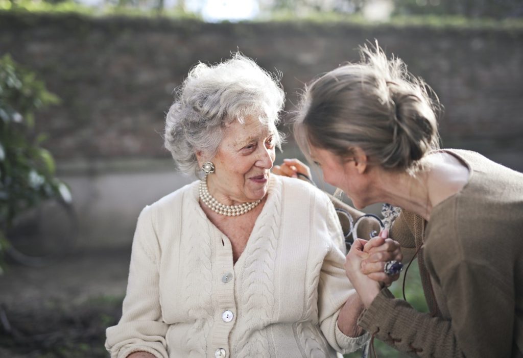 Older lady in a garden with a younger lady helping her and keeping her company