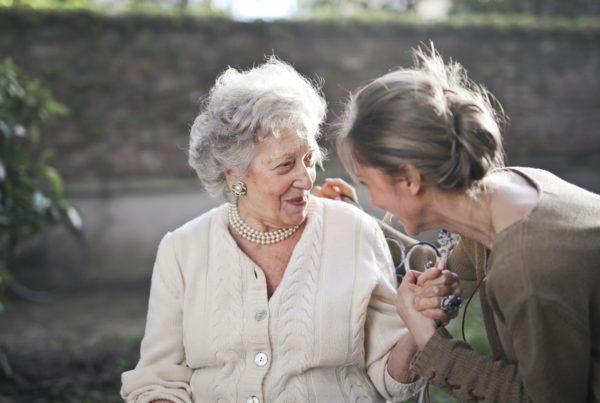 Older lady in a garden with a younger lady helping her and keeping her company