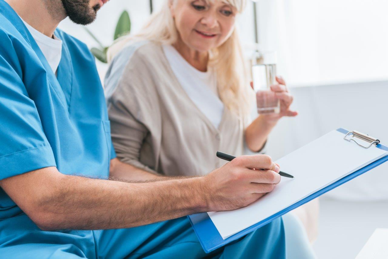 Male nurse talking to patient and taking notes